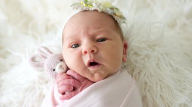 Sevimli yeni doğmuş bebek esniyor ve bir oyuncağa sarılıyor