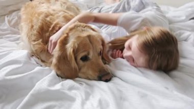 Neşeli genç kız yatağında sevimli köpeğiyle sarılıyor.