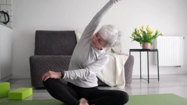 Gri saçlı, spor yapan ve evde esneme hareketleri yapan yaşlı kadınları cezbediyorsun.