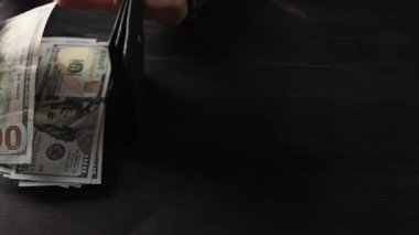 Kız, günlük harcamaları karşılamak için siyah bir cüzdandan para çekiyor.