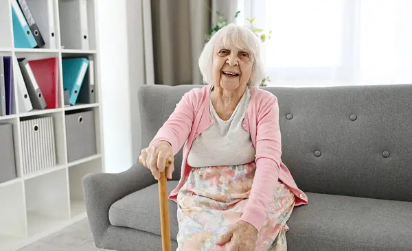 Oturma Odasındaki Koltukta Oturan Yaşlı Kadın Cane Gülüyor Kameraya Bakıyor — Stok fotoğraf