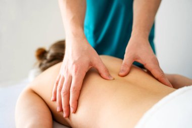 Spa salonunda sırt masajı yapan kız. Masör elleri, genç kadın sağlığı ve rahatlığı için vücut terapisi prosedürü uyguluyor..