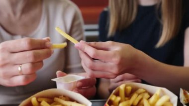 Anne ve küçük kızı fast food lokantasında sosla patates kızartmasının tadını çıkarıyorlar.