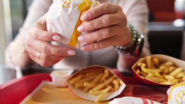 Poznan, Polonya - 28 Nisan 2024: Bir McDonalds Fast Food Lokantasında Bir Çizburger Yiyen Kadın