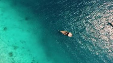 Zanzibar 'daki balıkçı köyünün yakınındaki okyanusun şeffaf sularında ıssız bir teknede insansız hava aracının inanılmaz görüntüsü.