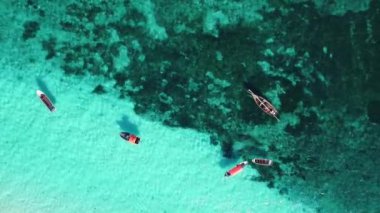Zanzibar 'daki balıkçı köyünün yakınındaki okyanusun şeffaf sularındaki bir teknede insansız hava aracından inanılmaz bir manzara.