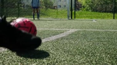 Koç, bir çocuk futbol antrenmanında futbol topunu tekmeliyor.