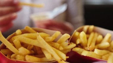 Fast Food 'ta soslu kızarmış patates yiyen bir kız.