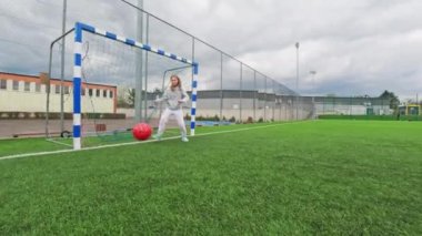 Futbol sahasında topu engellemeye çalışan küçük bir kız.