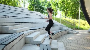 Formda bir kız sabah rutinine giriyor parkta spor yapıyor ve merdivenlerden yukarı koşuyor.