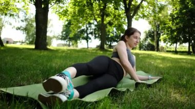 Sevimli, zinde genç bir kız direniş bantlarıyla spor yapıyor ve bacaklarıyla çalışıyor.