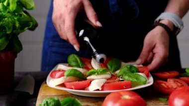 Mutfakta taze sebze Caprese salatası üzerine balzamik sosu döken kadın.