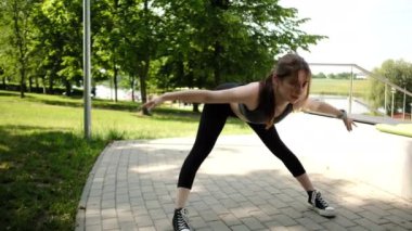 Parkta sabah rutininin bir parçası olarak egzersiz yapan ve esneyen formda bir kız.