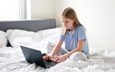 Hafta sonunun erken saatlerinde yatakta internette sörf yapan tatlı bir anaokulu kızı.