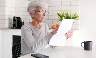 Orta yaşlı kadın dikkatle Finansal Mektup okuyor.