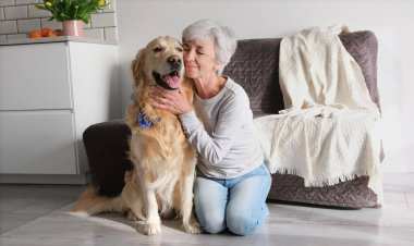 Neşeli yaşlı bayan içeride sevimli köpeğini okşuyor.