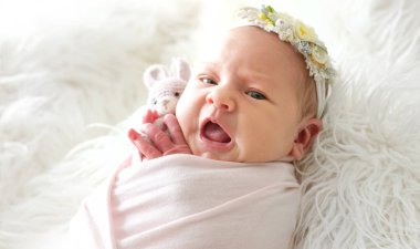 Örgü bir oyuncakla battaniyeye sarılı sevimli bir bebek.