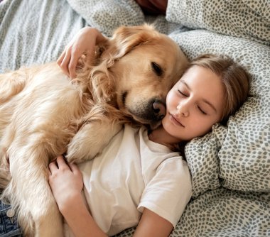 Yatakta köpekle yatan tatlı küçük kız.