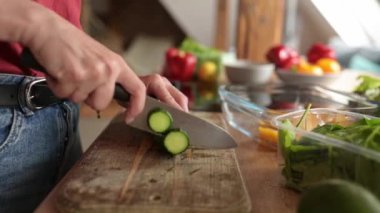 Sağlıklı sebze salatası için mutfakta salatalık kesen bir kız.