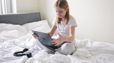Tatlı küçük kız sabahları kulaklık takıp laptopuyla oynuyor.