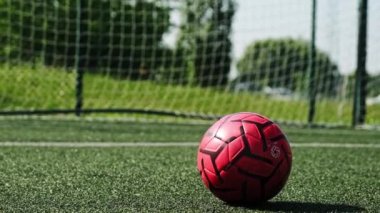 Futbol topu bir futbol sahasının yeşil çimlerinde dinleniyor.