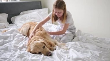 Neşeli genç kız, yatak odasındaki altın av köpeğiyle eğleniyor.