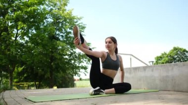 Parkta spor yapan ve bacaklarını esneten bir kız.