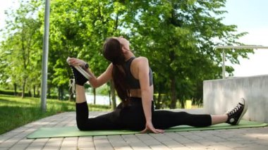 Parkta sabah rutininin bir parçası olarak esneme ve ayrılma da dahil olmak üzere spor egzersizleri yapan sağlıklı bir kız.