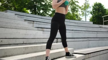 Formda bir kız parkta sabah egzersizi yapar ağırlık kaldırmak ve bir kettlebell ile çalışmak da dahil.