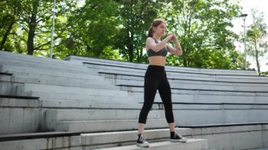 Ayaklarını güçlendirmek için dışarıda çömelme ve vücut geliştirme egzersizleri yapan genç bir kız.