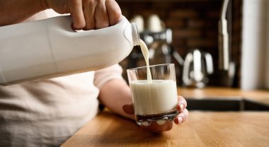 Evdeki mutfakta bardağa süt dökmek.