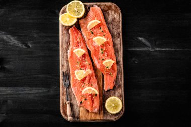 Tahta tahtada limonlu taze somon filetosu akşam yemeği için hazır. Omega portakal balığı ve turunçgiller sağlıklı beslenme için.