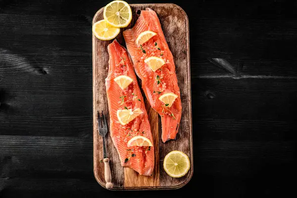 Tahta tahtada limonlu taze somon filetosu akşam yemeği için hazır. Omega portakal balığı ve turunçgiller sağlıklı beslenme için.