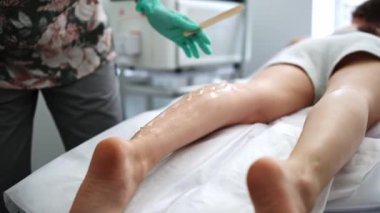 Spa kliniğinde vücut kılı temizleme prosedürleri, bacaklardaki lazer tüy epilasyonuna hazırlanıyor.