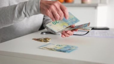 Mutfak tezgahındaki Euro notlarını sıralayan ve sayan yaşlı kadın.