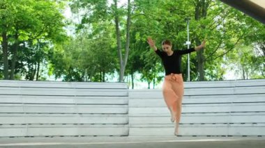 Genç kız dışarıda dans ederken tek eliyle takla atıyor.
