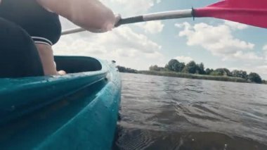 Kız, açık deniz etkinliğinin bir parçası olarak kürekle nehir yüzeyinde kano sürüyor.