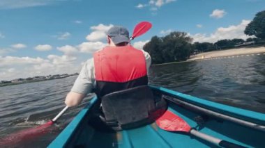 Can yelekli bir adam gölde kano sürüyor, açık hava su sporlarıyla ilgileniyor.