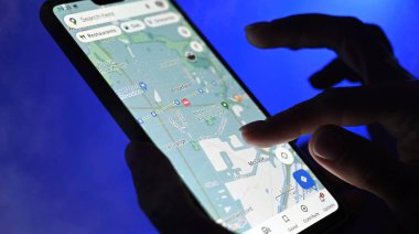 Poznan, Polonya - 13 Ocak: Google Maps uygulaması kullanan kız mavi arkaplana karşı akıllı telefon kullanıyor, görüntüyü kapat