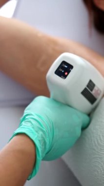 Doktor, bir güzellik kliniğinde lazer vücut kılları çıkarma prosedürü sırasında kadın koltukaltına epilasyon lazer cihazı uyguluyor.
