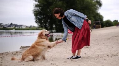 Kadın sahibi Golden Retriever 'a pençe atmayı öğretiyor. 