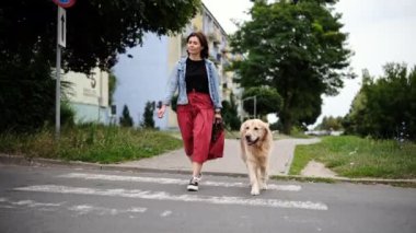 Tasmalı bir kadın yaya geçidinde karşıdan karşıya geçiyor, caddede yürüyor.