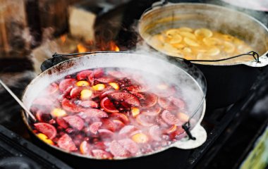 Meyve ve böğürtlen içecekler, sıcak sıcak şarap, tencerelerde pişmiş buharlı sokak yemekleri. Açık hava festivalinde renkli, sıcak, tatlı içecekler.