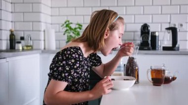 Mutfakta kahvaltıda kuru mısır gevreği yiyen tatlı küçük kız.