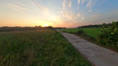 Fpv Drone kırsal bir arazide ve gün batımında uçuyor.