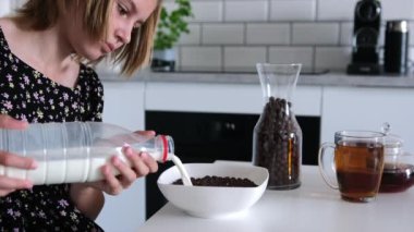 Kahvaltıda mısır gevreği yiyen, kaseye süt döken tatlı küçük kız.