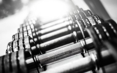 Modern bir spor salonunda arka arkaya metal dambıllar.