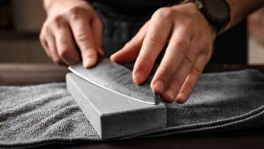 Bıçağı bileme taşı ile keskinleştiren adam, yakın çekim görüntüsü