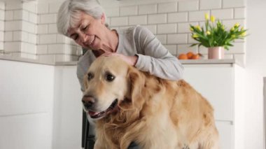 Neşeli yaşlı kadın gülümseyerek sevimli köpeğini kucaklıyor.
