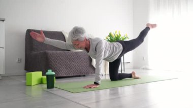 Evde yoga yapan yaşlı aktif bayan.